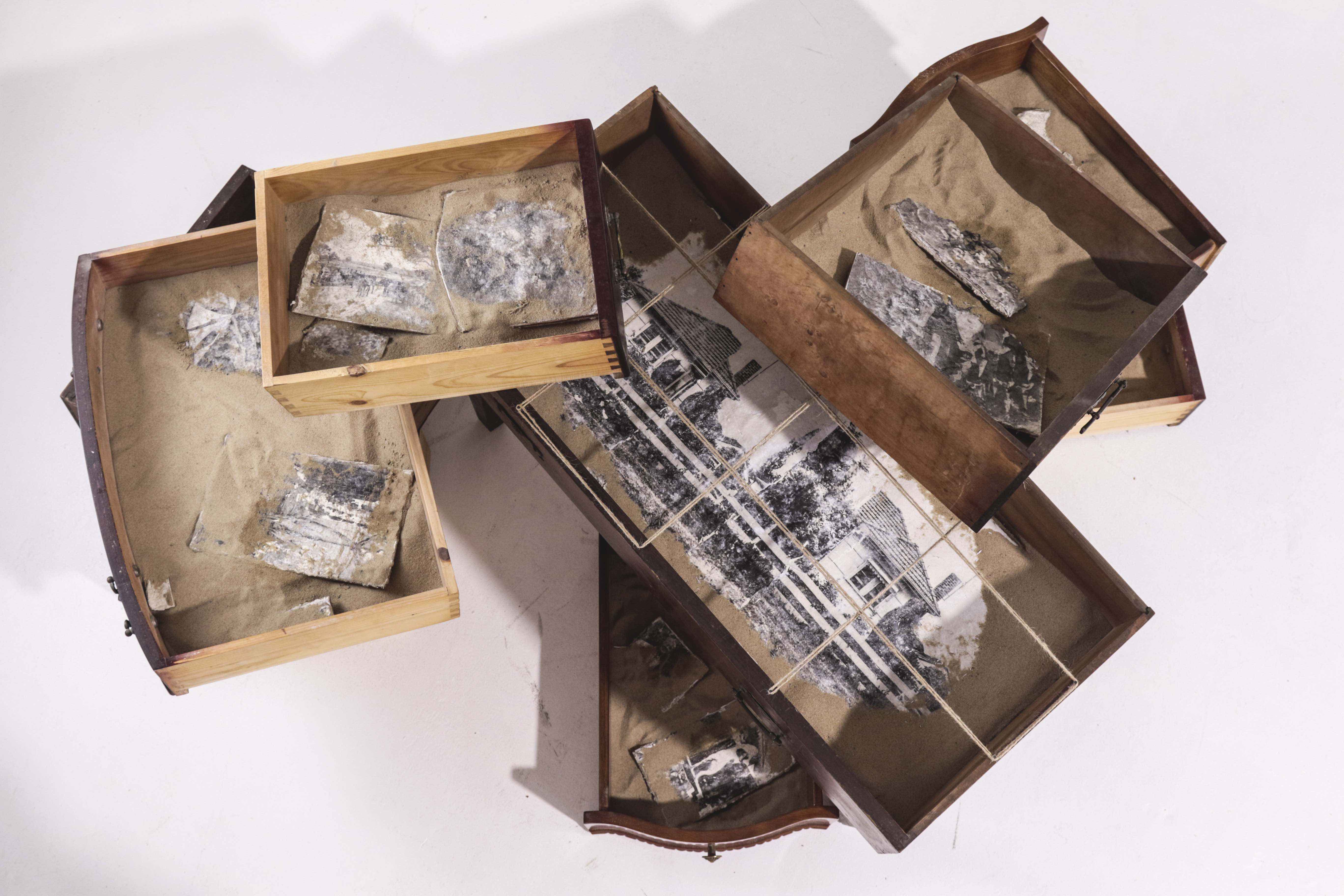 Found objects (drawers), sand, paper clay, photo transfers. 
