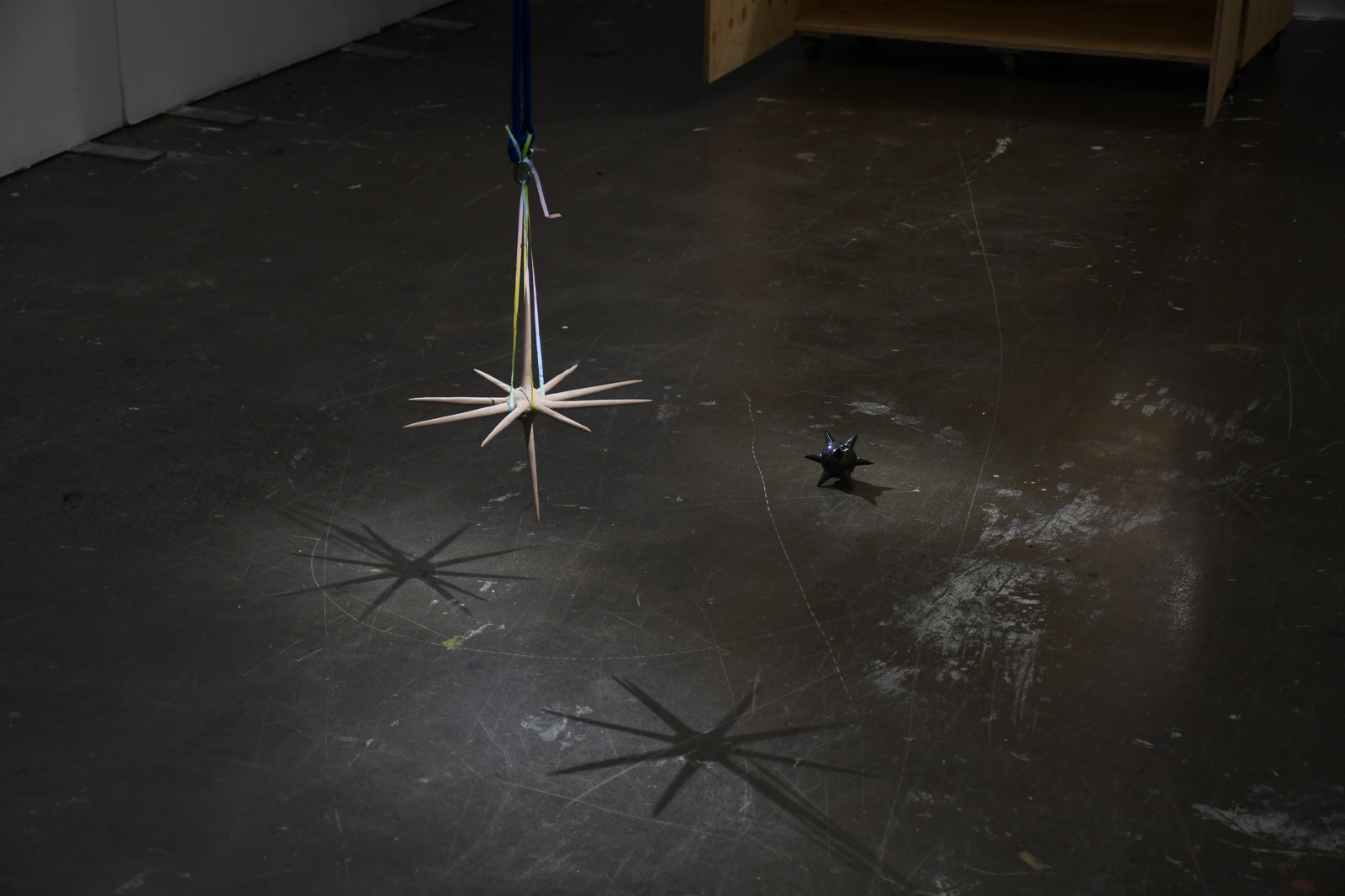 'In waves', 2024. Earthenware and glaze, unfired BRT, gift wrap ribbon, carabiners, nylon rope.