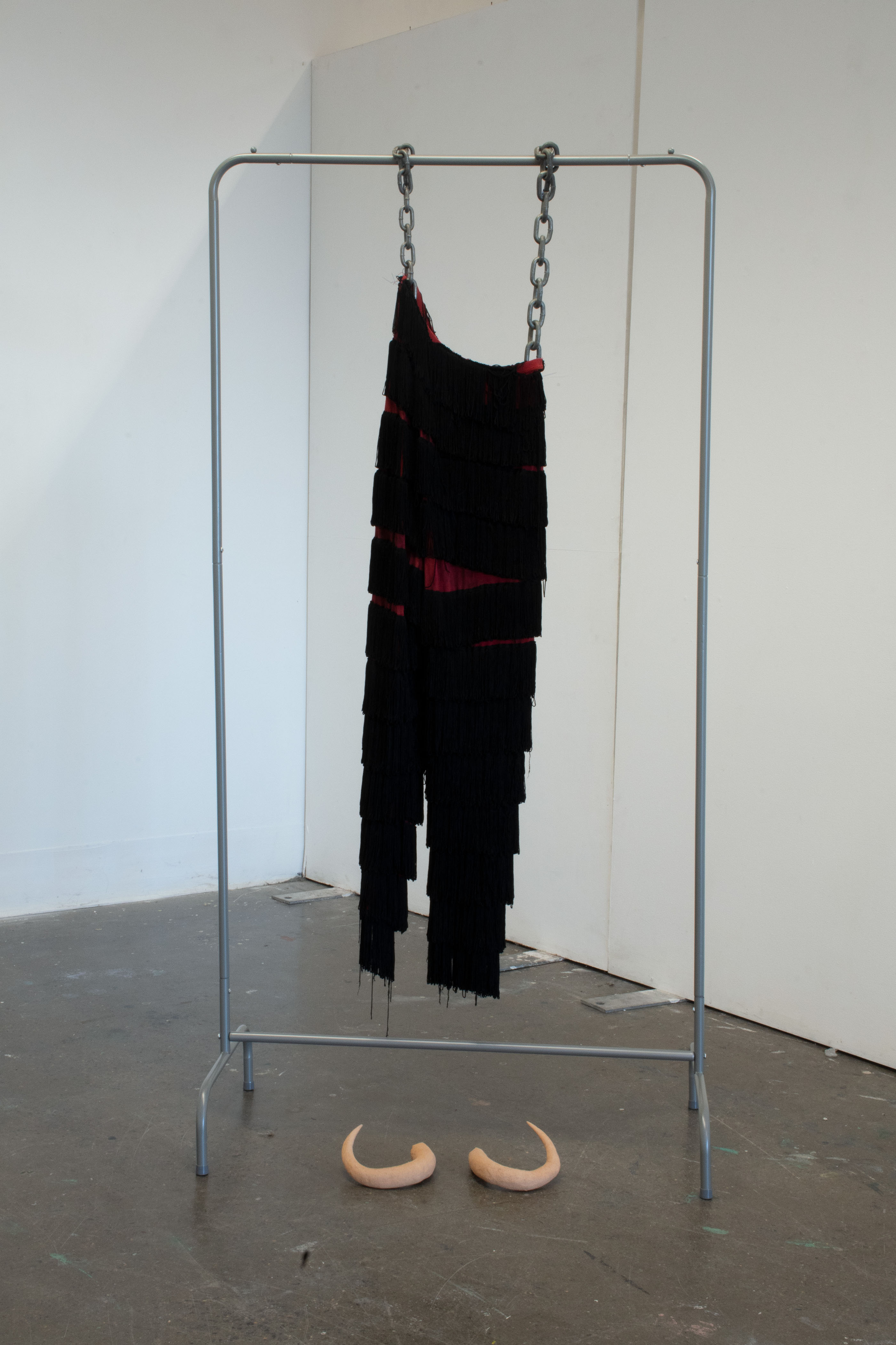 'HORNS', 2024. Earthenware, tassled pants, clothes rack, chain and wire