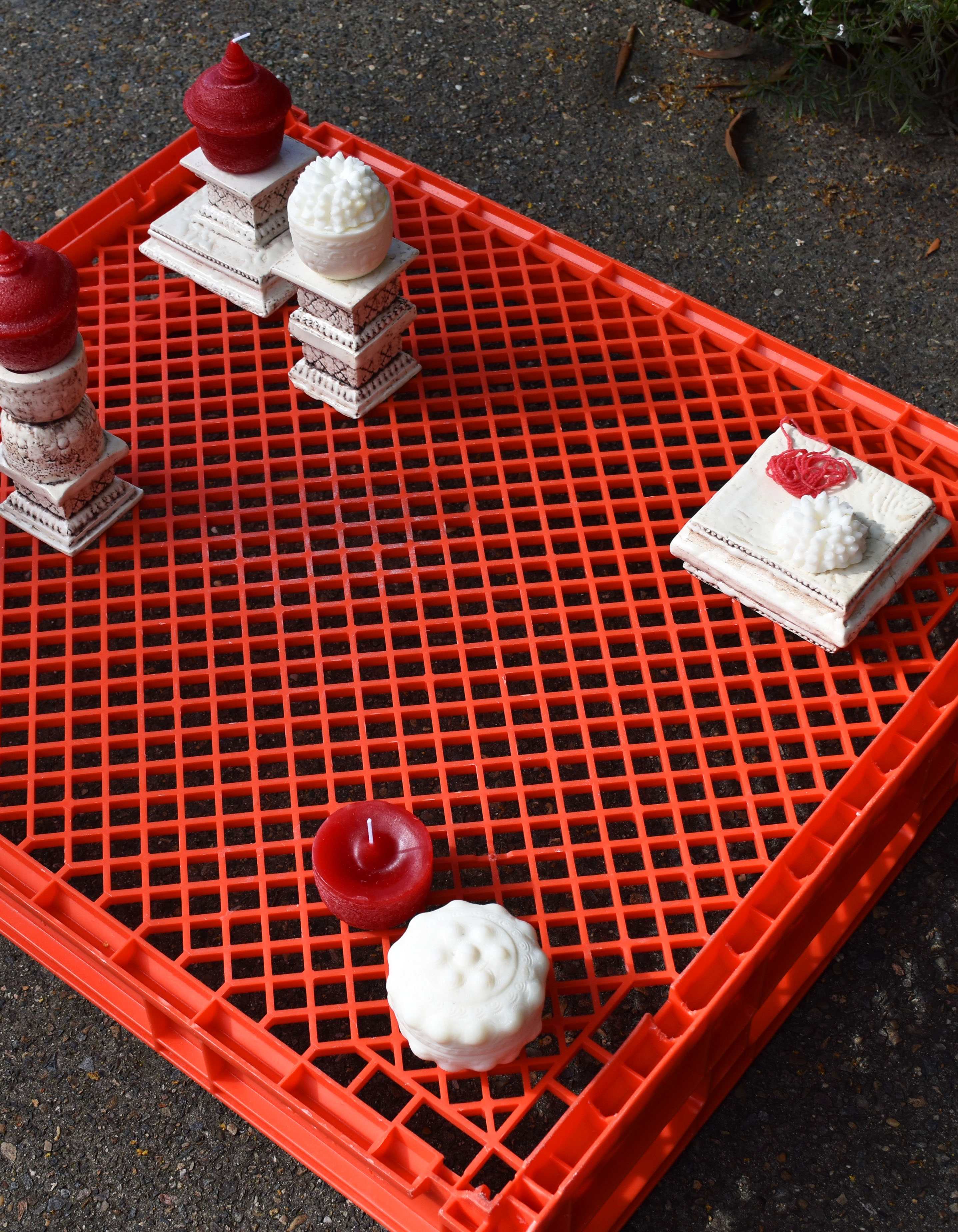 'meld into the shape of mother's motherland', 2025. Wax, lamp wicks, slip clay, manganese oxide, satin white glaze, plastic pallet