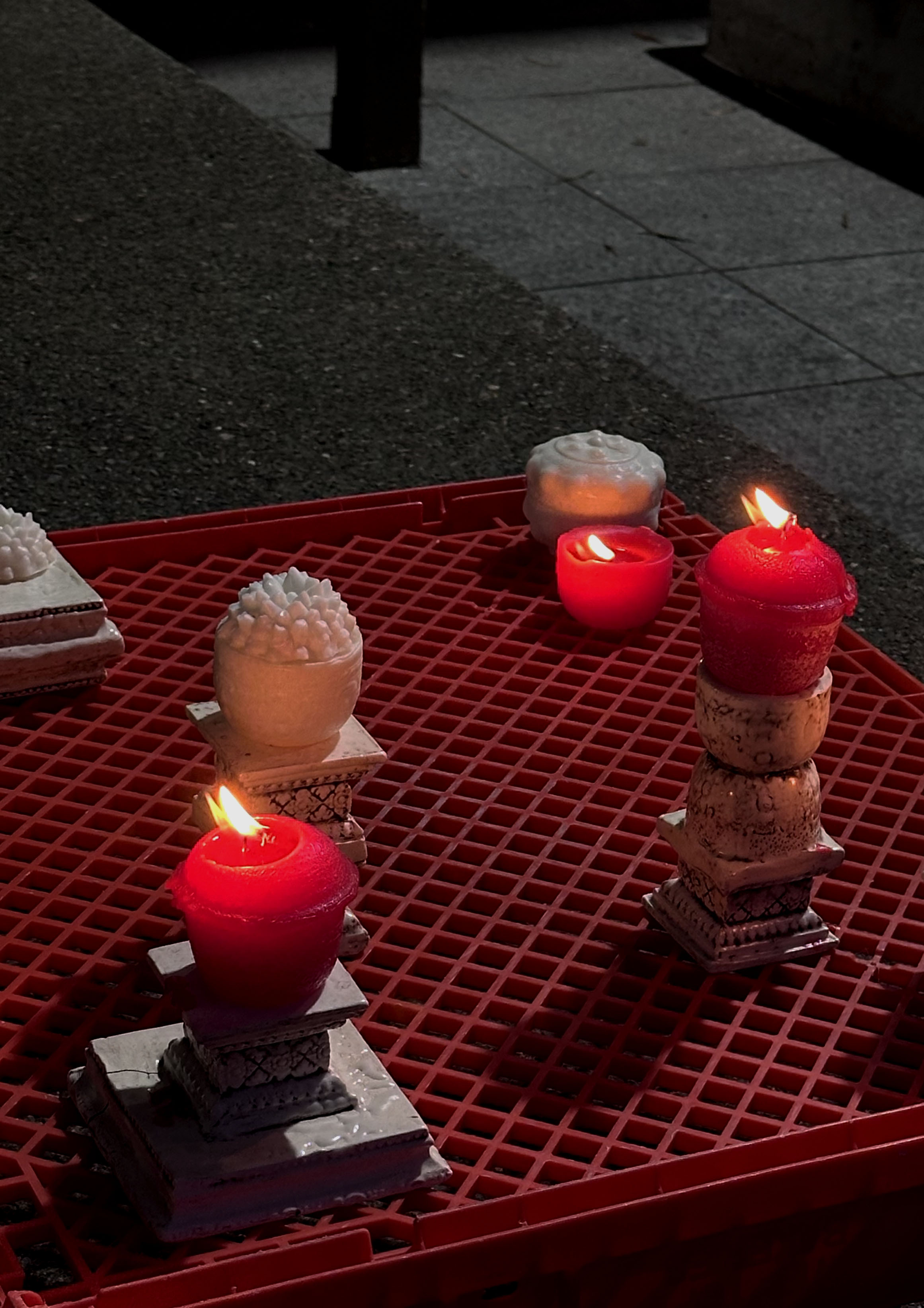 'meld into the shape of mother's motherland', 2025. Wax, lamp wicks, slip clay, manganese oxide, satin white glaze, plastic pallet