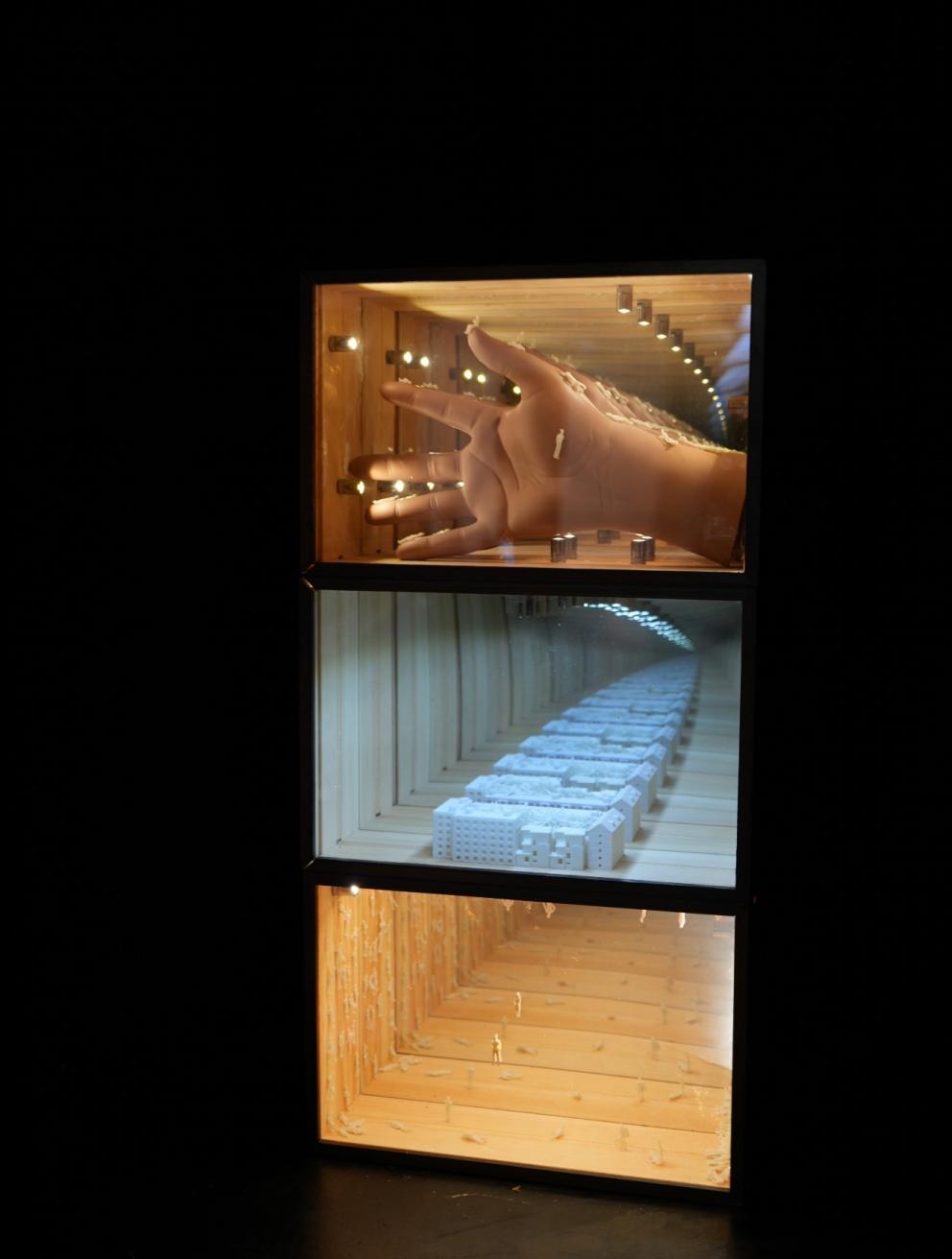 'Loop: Replaying Your Fate Inside', 2025. Mirrored acrylic (two-way), glass mirror, wood box, plastic model hand, miniature figures, 3D-printed PLA parts, coin-cell button lights.